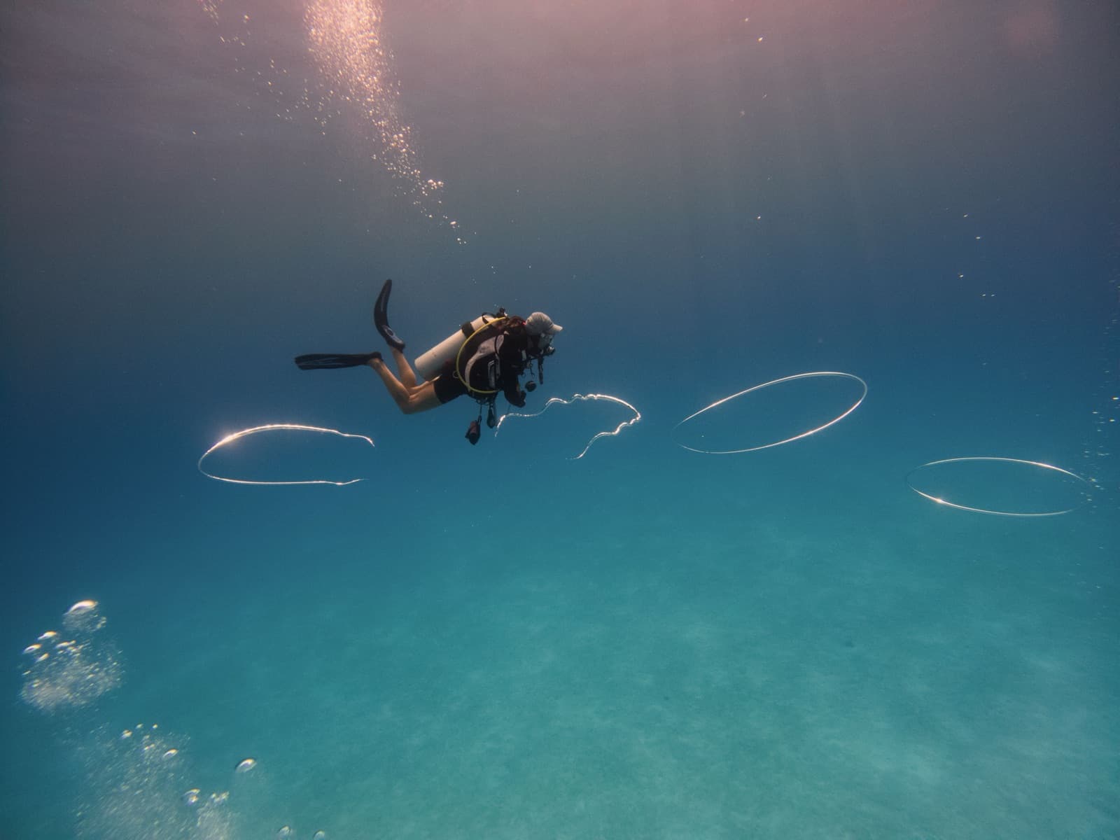 A scuba diver blowing bubble rings in San Salvador's crystal-clear water