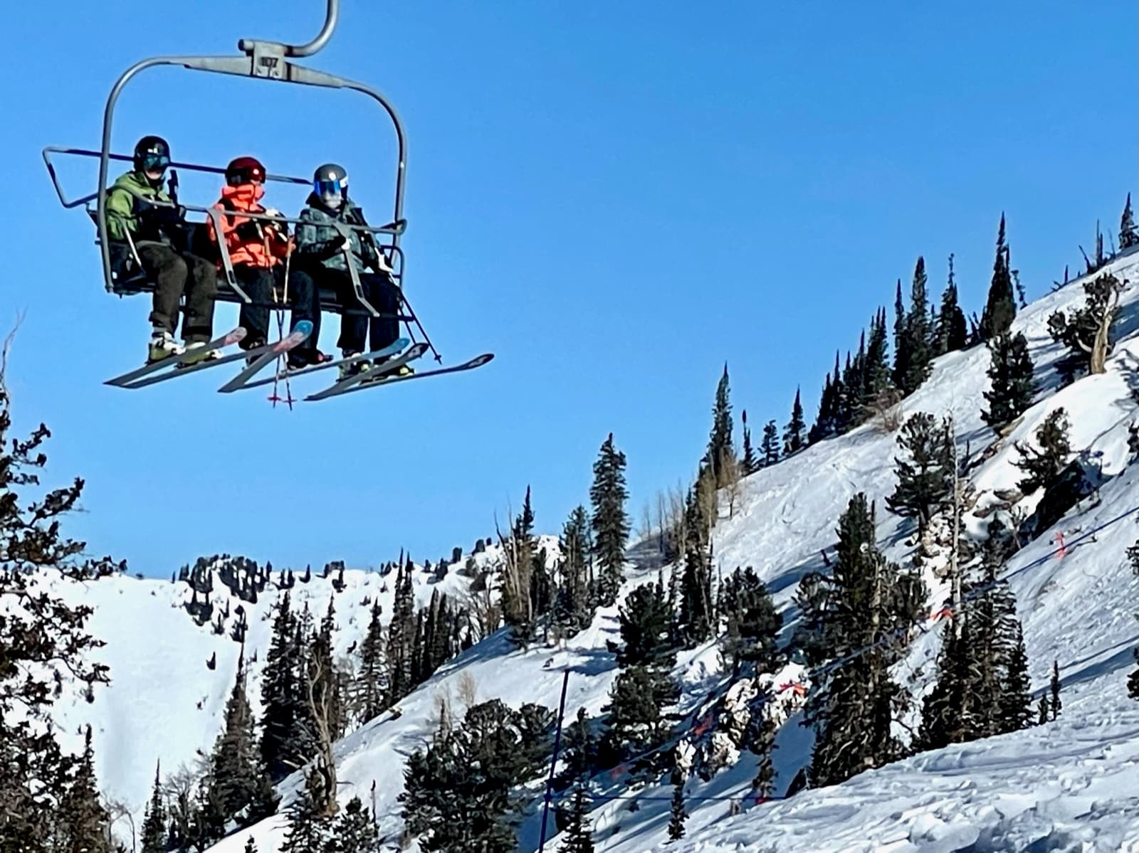 Three skiers riding the chairlift on a bluebird day