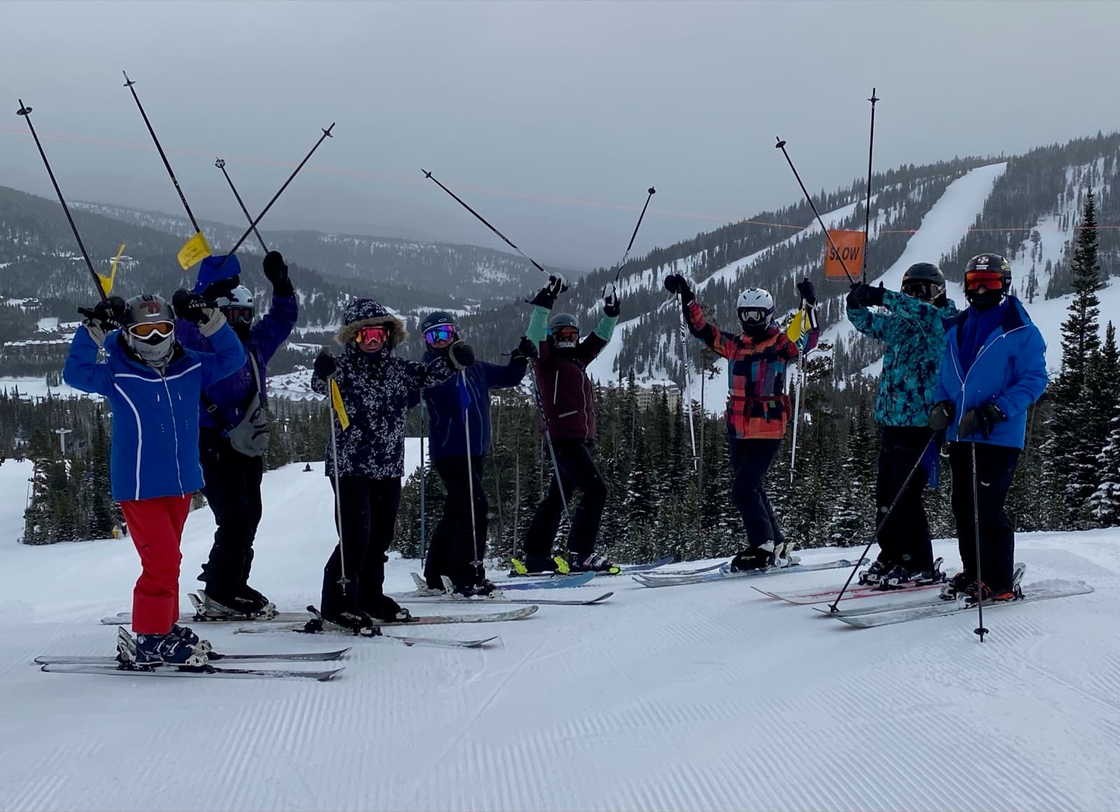 Eight skiers with poles raised above the valley