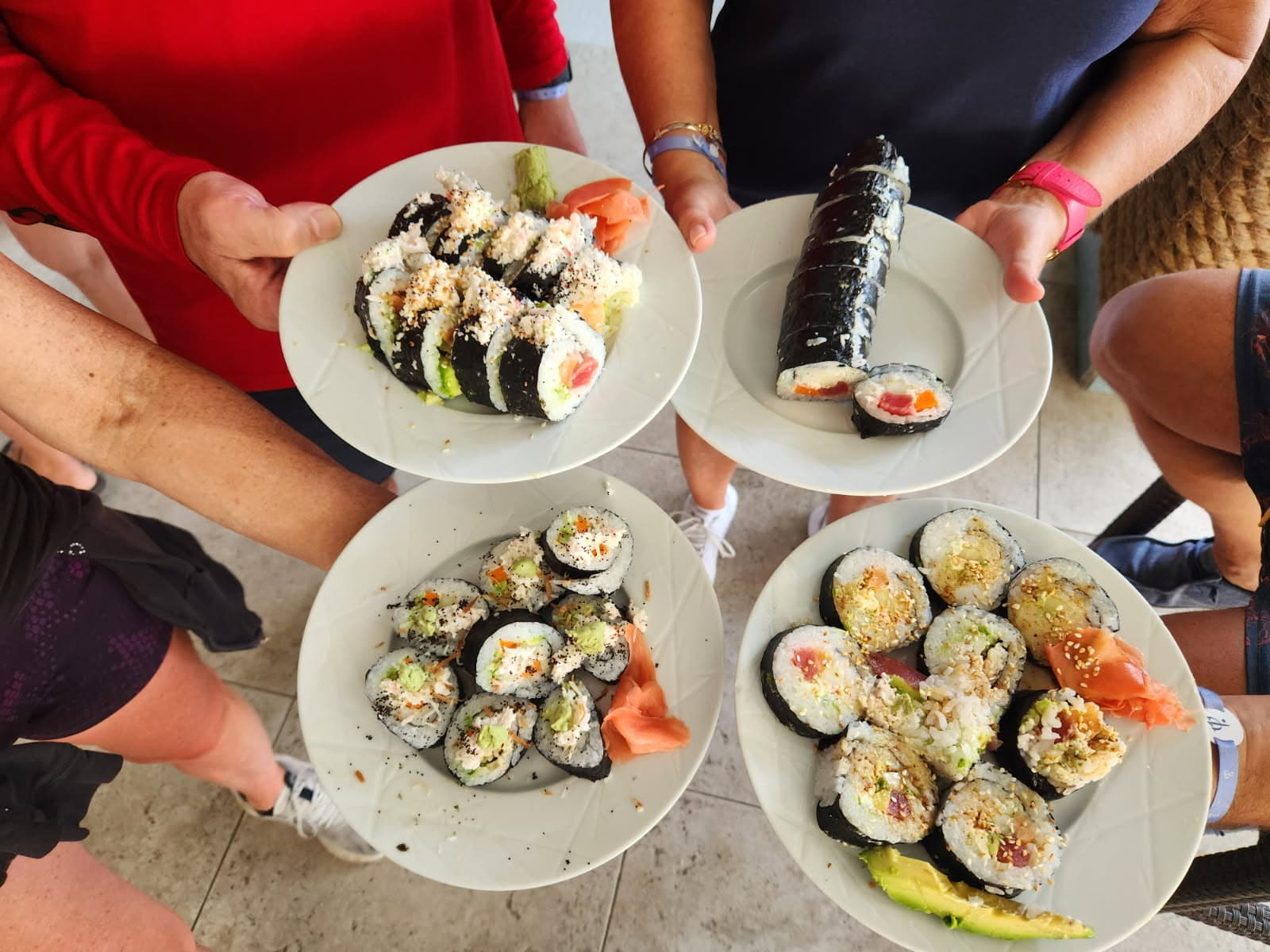 Four plates of hand-rolled sushi held up after a resort sushi class