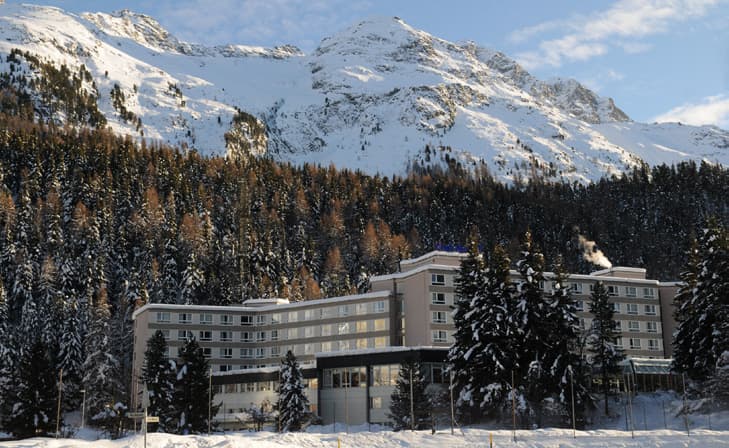 Club Med Saint-Moritz Roi Soleil nestled among snow-covered fir trees below the peaks
