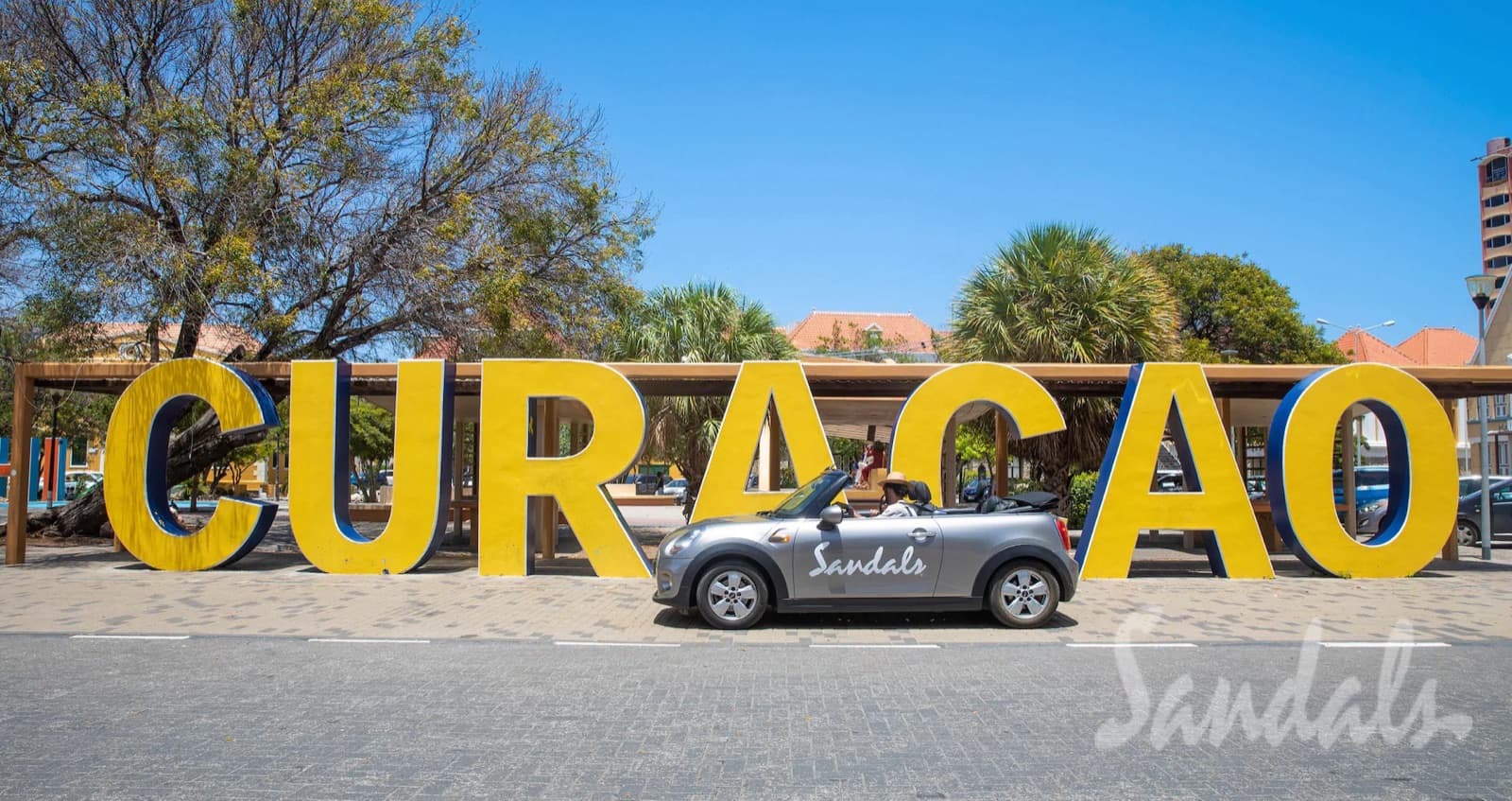 A Sandals MINI Cooper parked at the Curaçao sign — the Island Inclusive drive for butler-level stays
