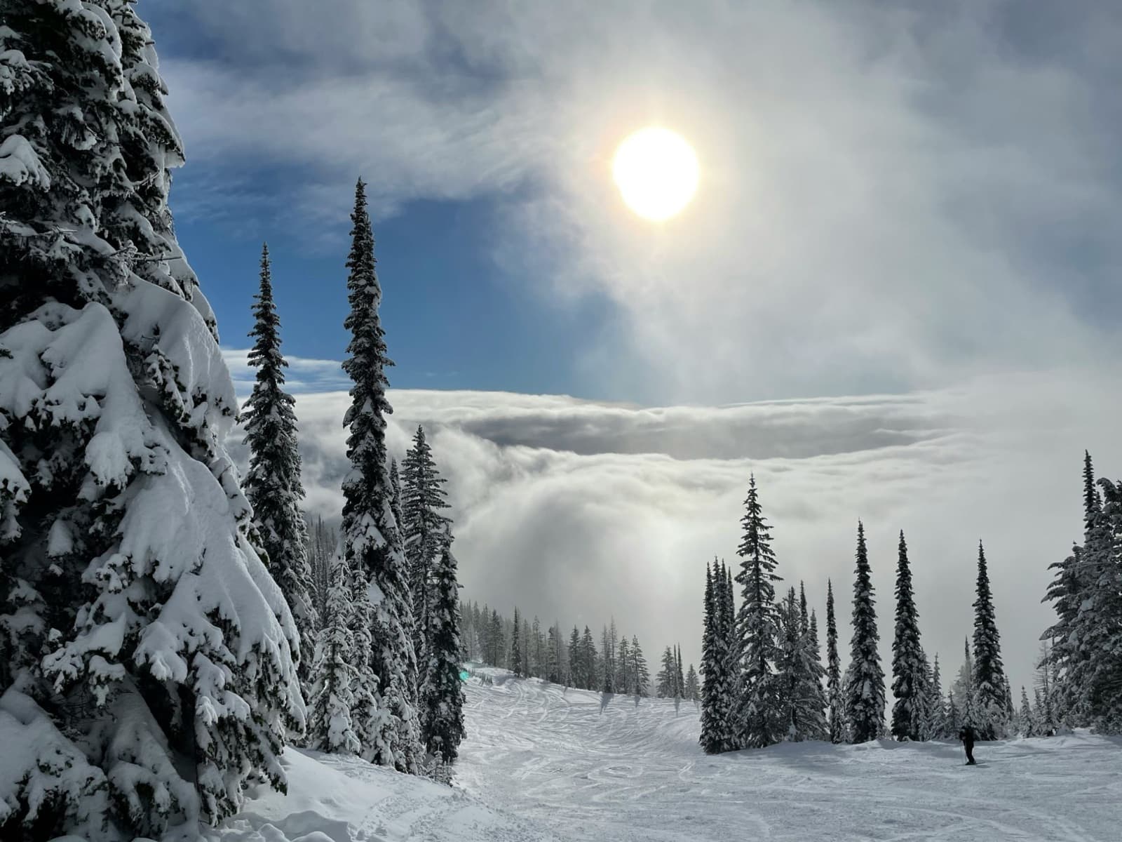 The sun burning through clouds above a valley inversion, seen from the snowy slopes of Whitefish Mountain