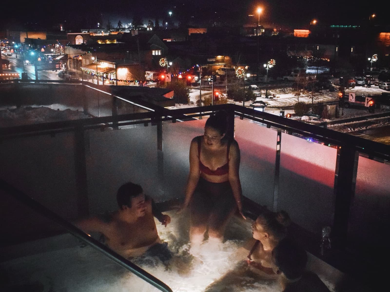 Friends in The Firebrand's rooftop hot tub at night, downtown Whitefish lit up below
