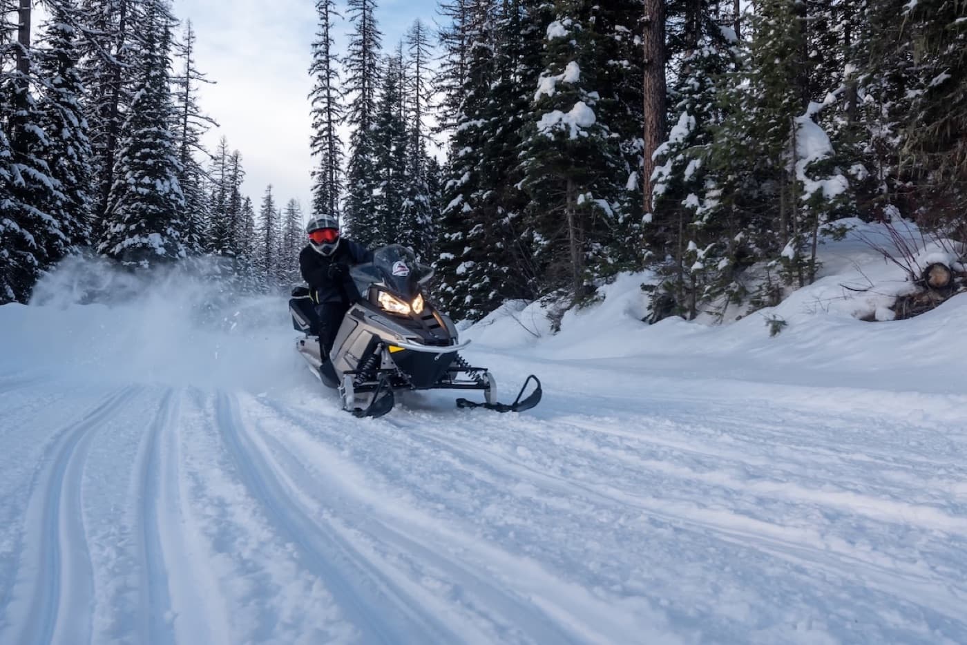 A snowmobiler carving up a snowy forest trail outside Whitefish