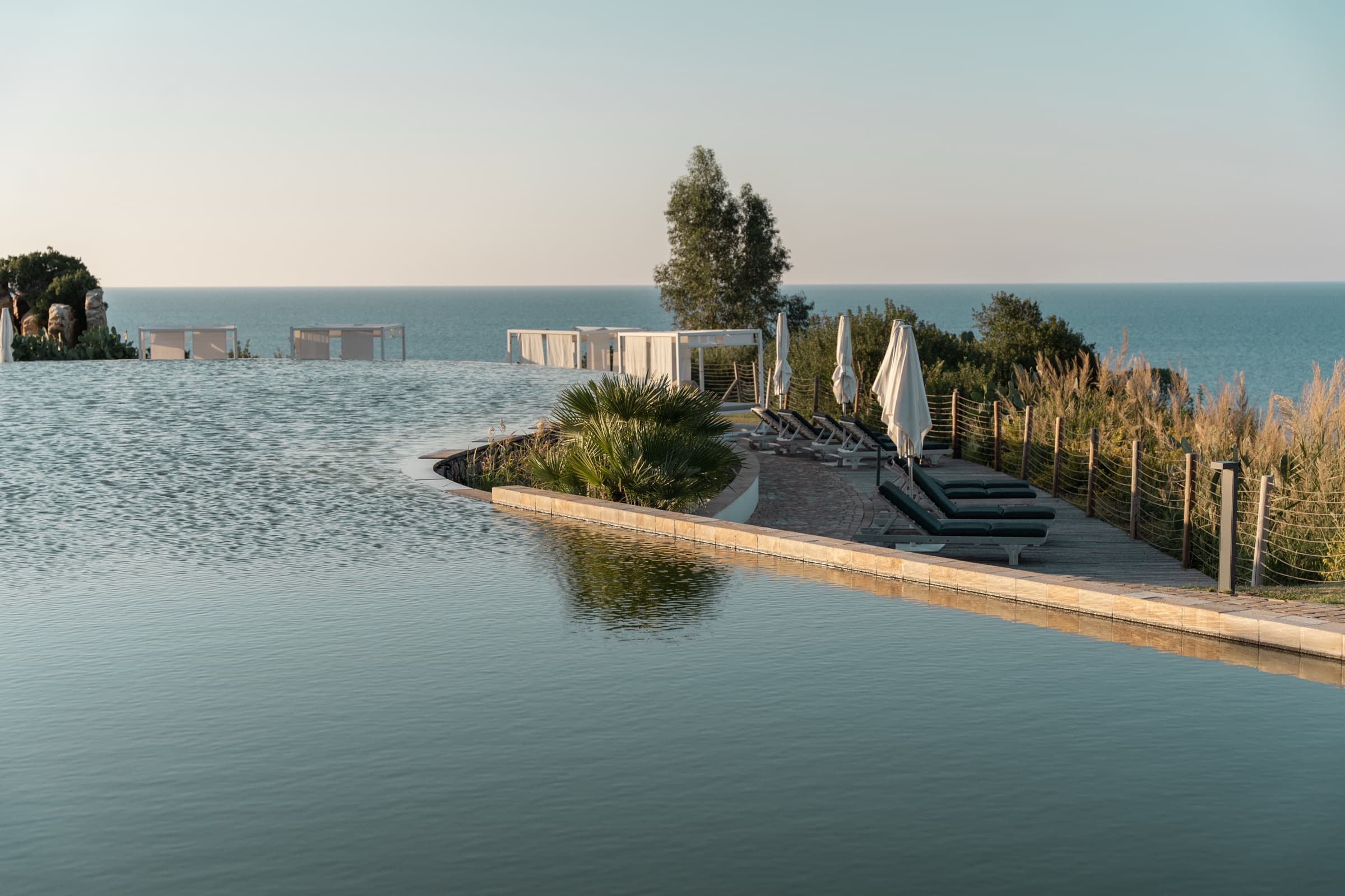 The infinity pool at Club Med Cefalù pouring into the sea horizon at golden hour