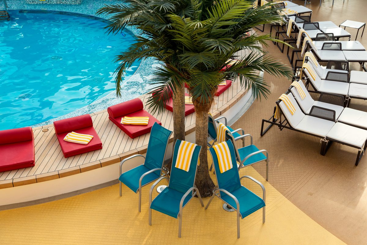 Palm-shaded resort pool deck lined with loungers