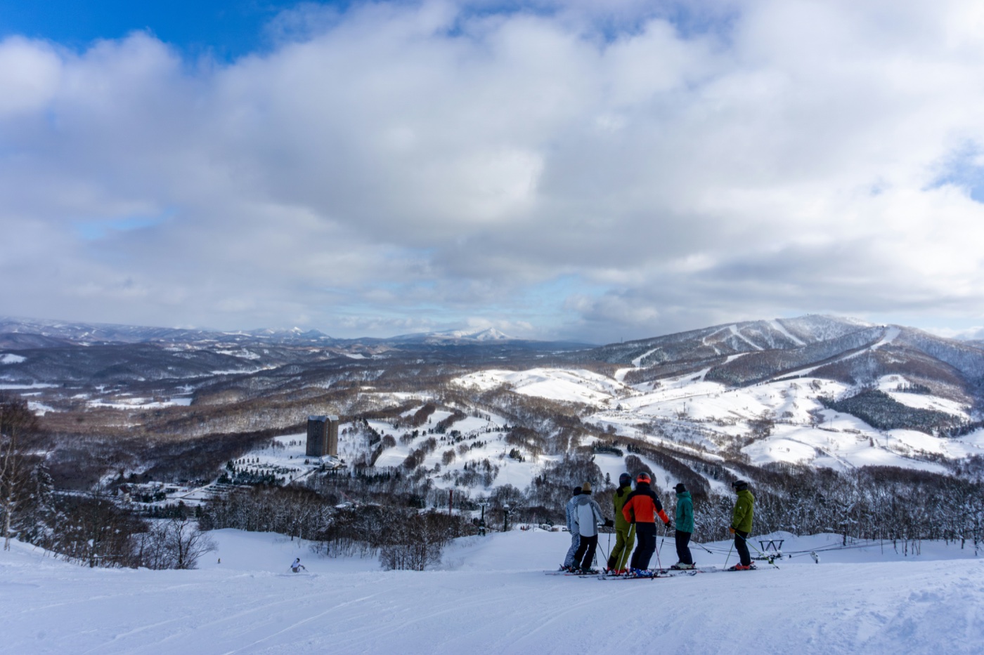 Friends gathered on a ski run above a sweeping valley