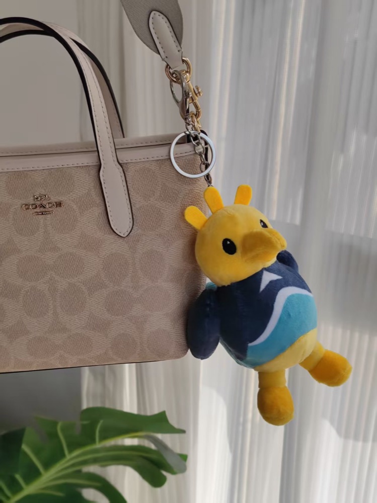 The real Sandigo plush keychain clipped to a travel bag