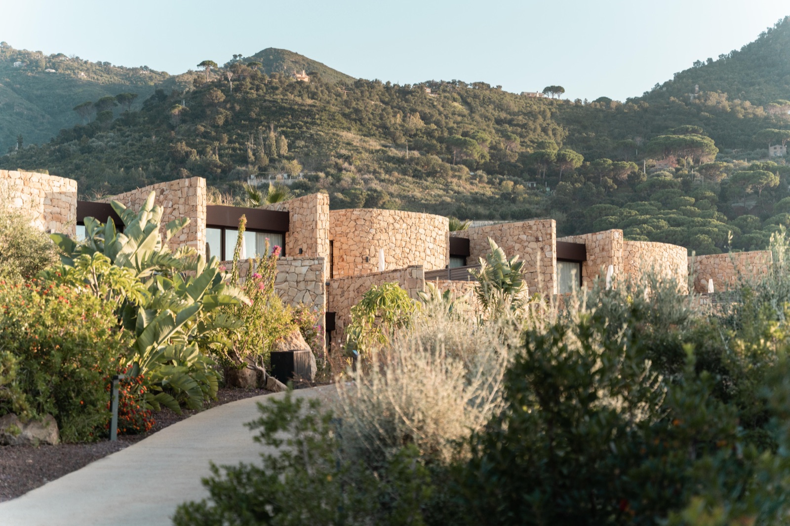 Stone villetas in hillside gardens at Club Med Cefalù, green Sicilian hills behind