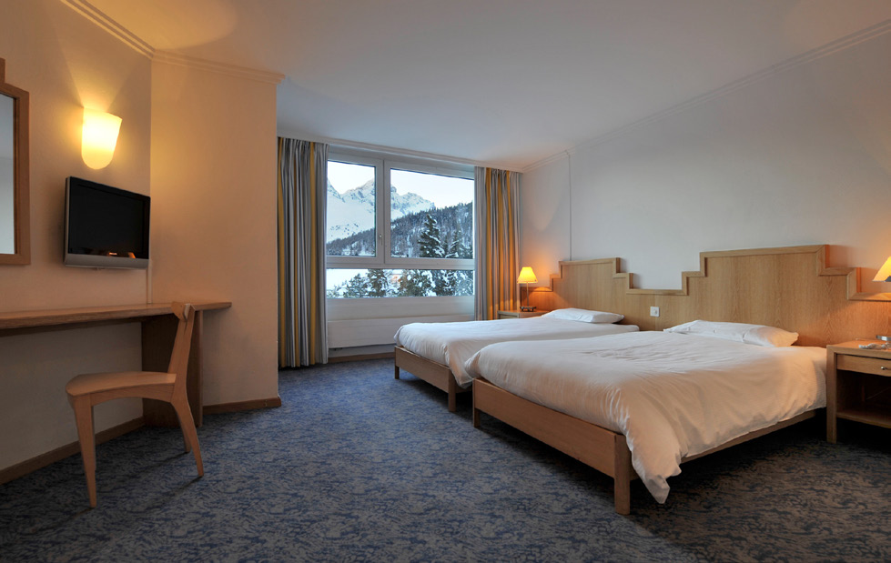 A Superior room at Club Med Saint-Moritz with twin beds, wood furniture, and a mountain view out the window
