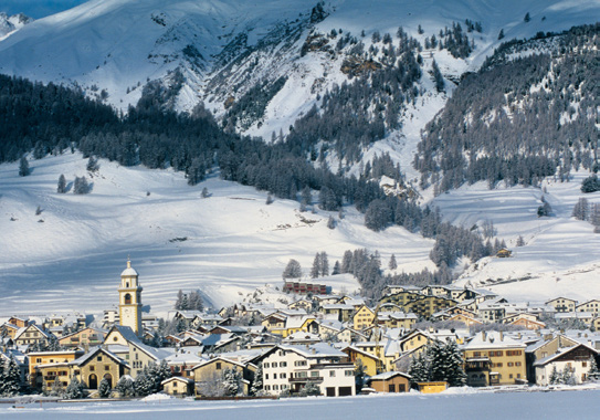 The snow-covered village of St. Moritz below the Engadine mountains, church tower rising from the rooftops